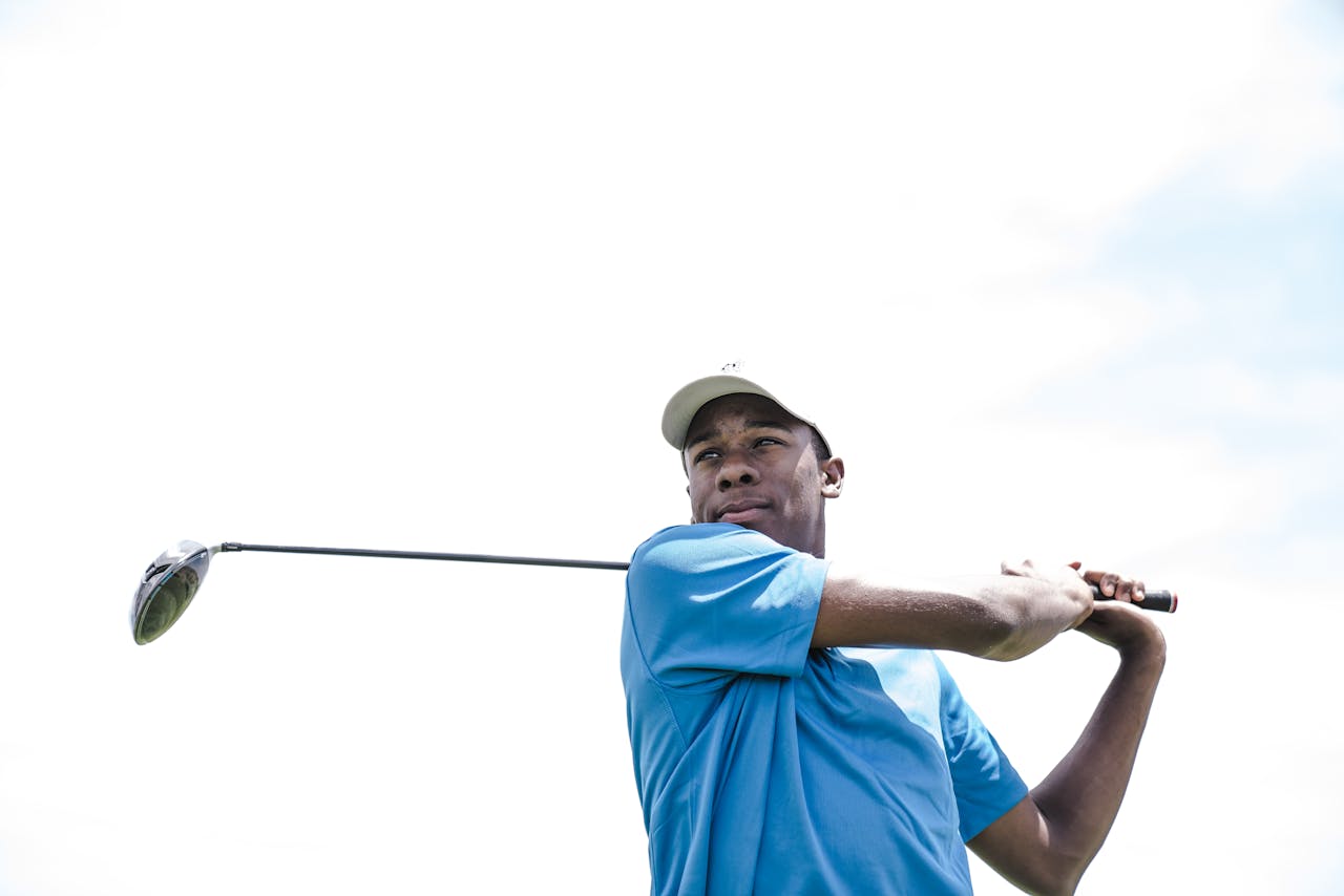 Mastering the First Impression: Your intriguing post title goes here African American man playing golf against a bright sky, mid-swing.